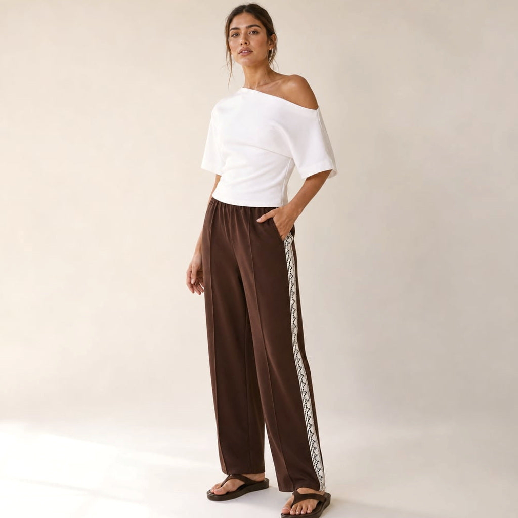 Modell trägt die Isaiah Plissee-Trackpant in Schokobraun mit Lace-Trim, kombiniert mit hellem Oberteil
