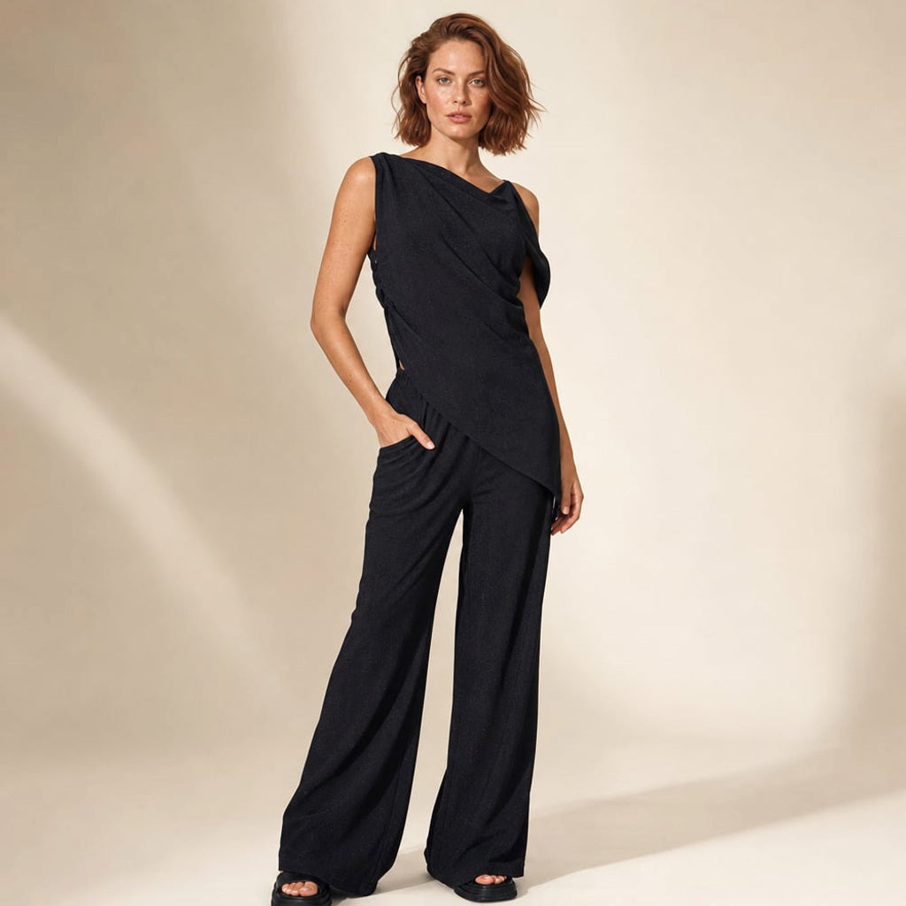 Schwarzes asymmetrisches Off-Shoulder-Co-ord-Set mit weiter Baumwollhose, Ganzkörperansicht auf hellem Hintergrund