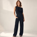 Model trägt schwarzes Off-Shoulder-Set mit diagonalem Ausschnitt und weit fallender Hose