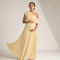 Schwangere Frau trägt apricotfarbenes One-Shoulder Maxi-Kleid mit weitem Fall bis zum Boden